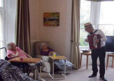 Bing Lyle entertaining Loose Valley Care Home residents in their lounge with his accordion