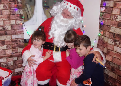 Three young children cuddling Santa at the Loose Valley Christmas party