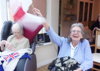 Lady resident at Loose Valley Care Home waving an England card