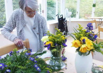 Lady resident making up some fresh flower arrangements in vases