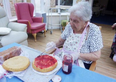 Lady resident spreading jam on a cake