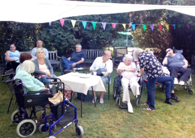 Loose Valley residents and visitors sitting in the garden under a gazebo during the summer fete