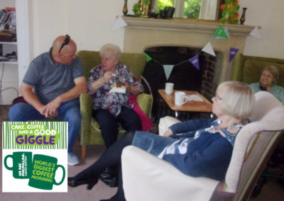 Residents and staff chatting over coffee and cake