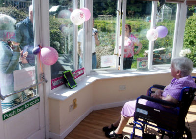 Resident on her birthday talking with family outside the conservatory at Loose Valley Care Home