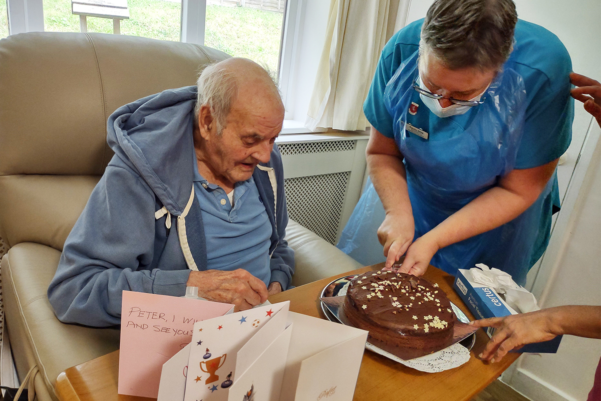 Loose Valley Care Home resident with his chocolate birthday cake being cut for him